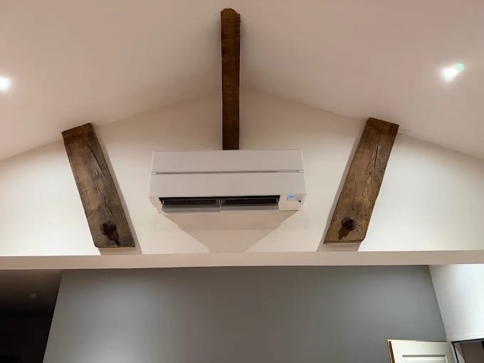 Climatisation murale installée sous combles avec poutres apparentes