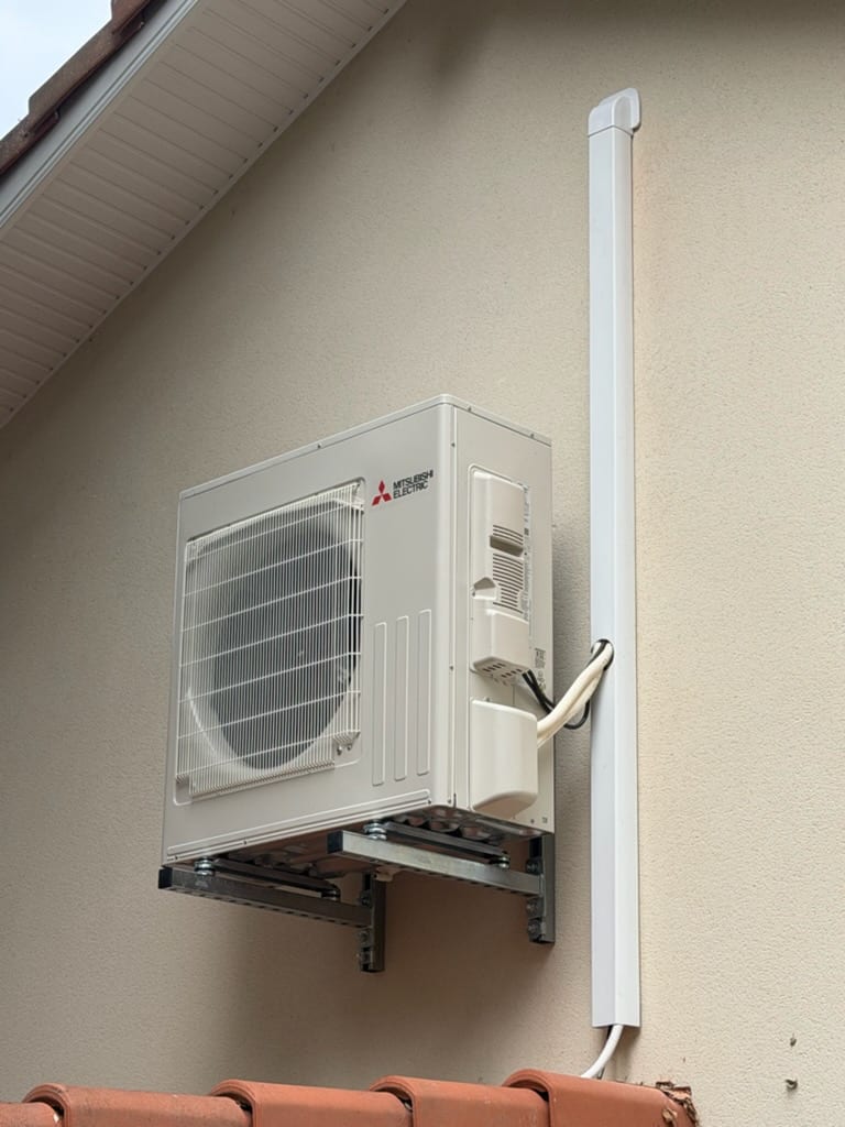 Unité extérieure Mitsubishi Electric posée en façade avec goulotte